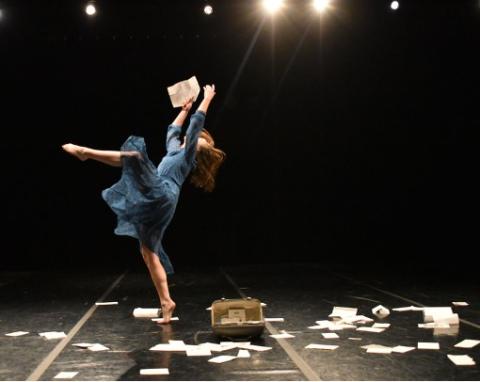 Ashley Mott dances on stage with paper