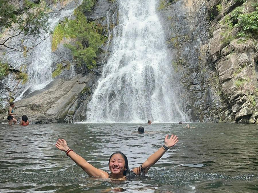 woman swimming in natural pool in front of waterfall in Australia