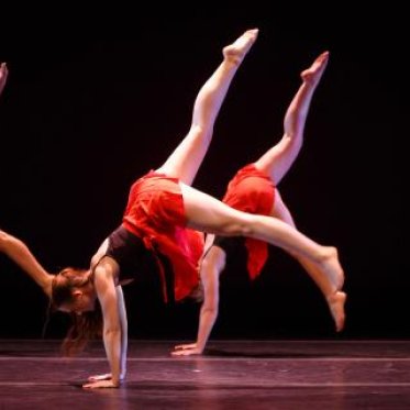 Dancers wearing similar clothing of black tanktops and a red skirt
