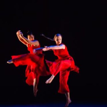 Two women in red in the middle of a dance pose
