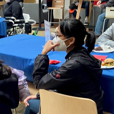 two women wearing masks sitting opposite to each other on a table