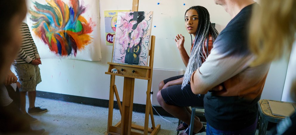 a student is presenting her painting in front of an art class