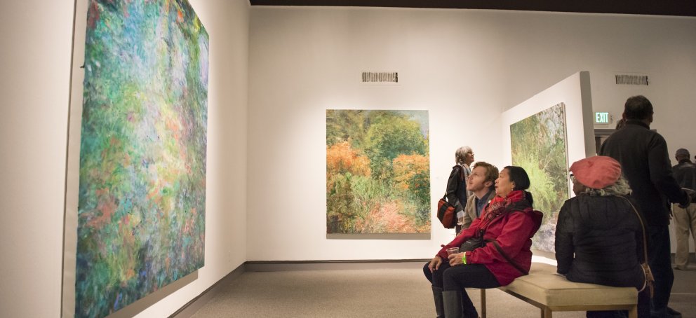 Visitors look at painting in the gallery.